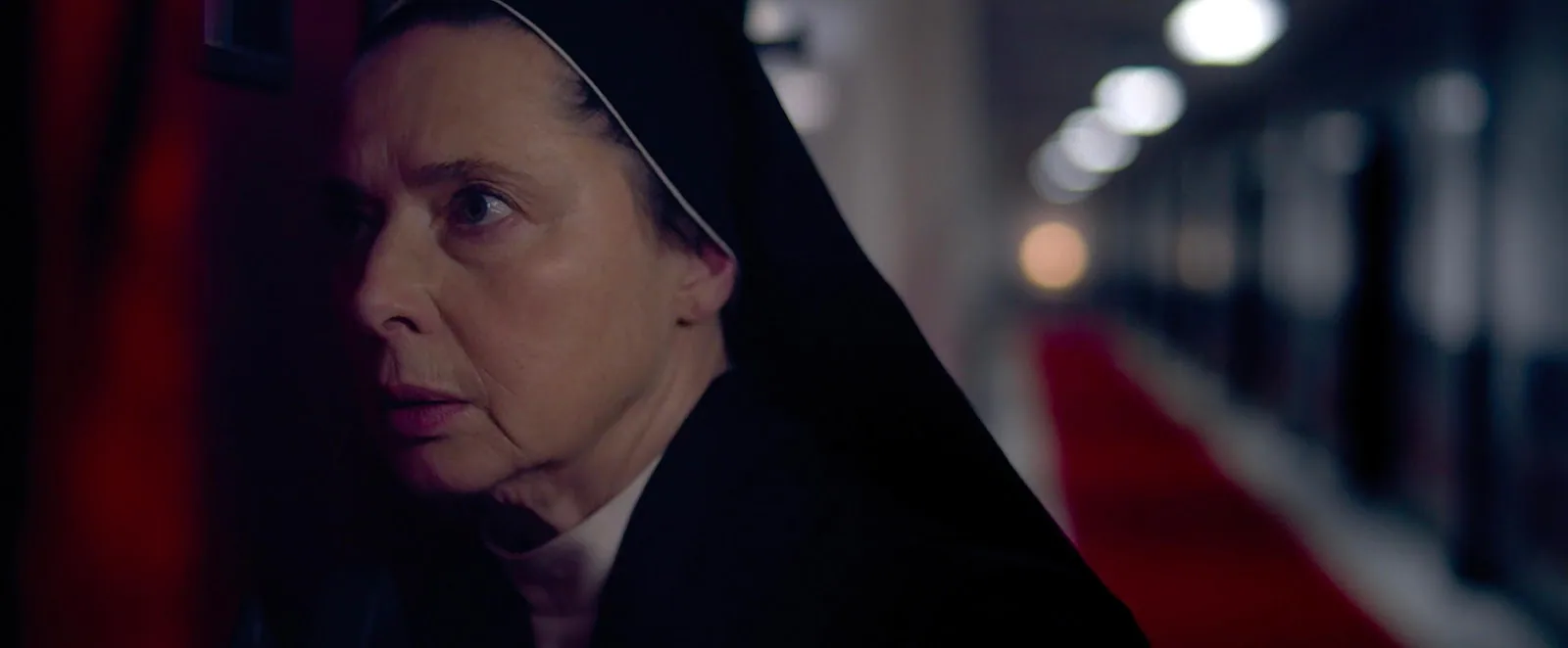 Isabella Rossellini in a white nun's habit and dark veil in a stone-walled passage